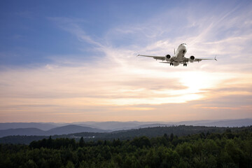 Airplane flying in sky over mountains in morning