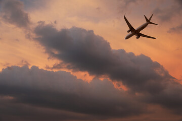 Airplane flying in beautiful sky with clouds at sunset
