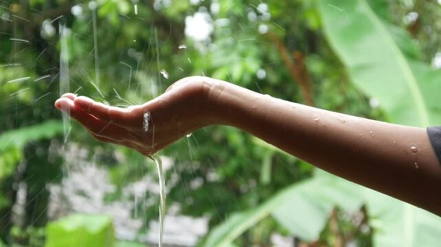 hand with falling raindrops creating water splashes