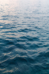 Serene waves gently lap against the shore during a calm evening, reflecting the soft colors of the sunset