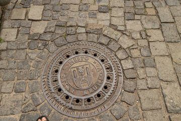 Cesky Krumlov, Czech Republic. Wet Metal Manhole cover with the inscription 