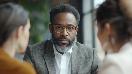 Obraz premium Focused Businessman Engaging in Conversation with Two Colleagues
