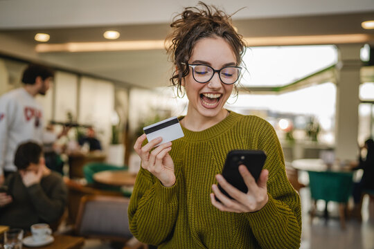 young woman use credit card for online shopping on cellphone at cafe