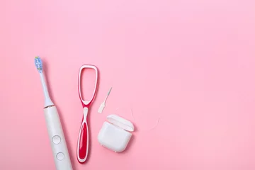 Daily dental care essentials include toothbrush, floss, and interdental cleaner on a soft pink background