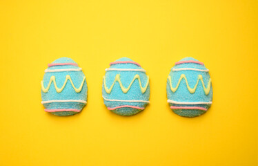 Three blue marshmallow Easter eggs are neatly arranged in a row on a soft yellow background. Minimalistic holiday composition perfect for festive branding, design, and seasonal marketing.