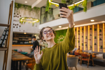 young cheerful woman stand and wave while have video call on cellphone