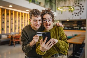 young happy couple use credit card for online shopping on mobile phone