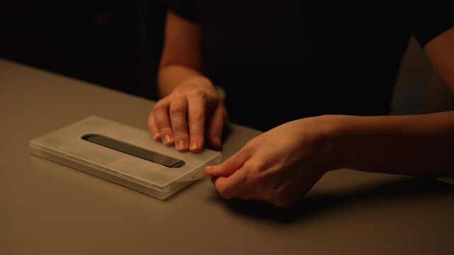 Close-up of technician female using special device to precisely apply protective film to smartphone screen, ensuring perfect fit and safeguarding mobile phone from scratches and damage, slow motion.