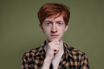 Cute teenage boy with freckles on dark green background