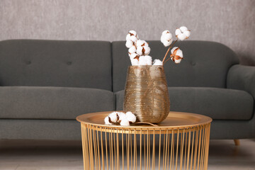 Coffee table with cotton flowers near sofa at home