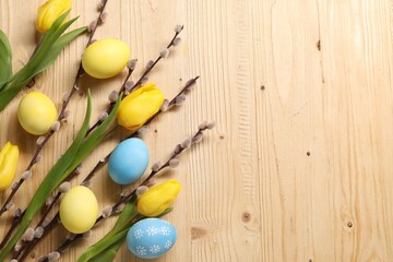 Easter eggs, beautiful tulips and willow branches on wooden background, flat lay. Space for text