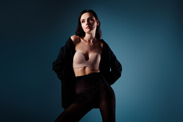 Confident young woman posing with elegance in a black jacket against a blue gradient background