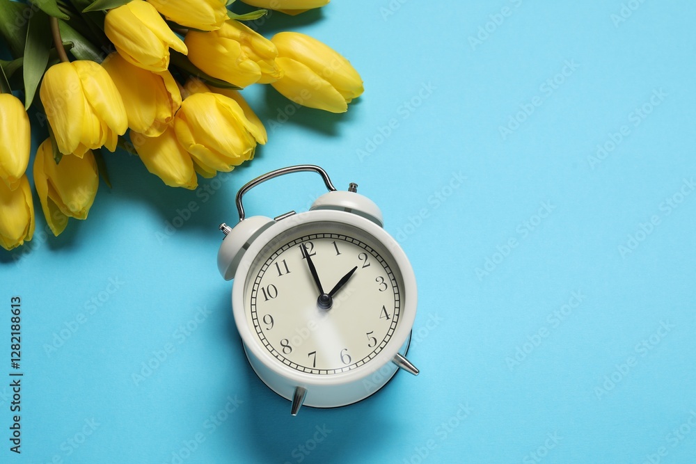 Poster spring time. alarm clock and beautiful tulips on light blue background, above view. space for text
