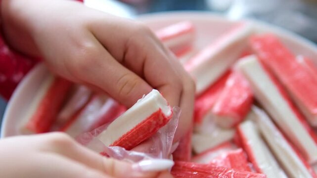 Cooking Crab Salad. The female hand cuts the ingredient crab sticks with a knife on the board. Holidays are coming soon. High quality 4k footage
