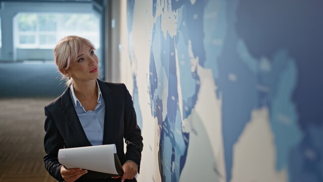 Inspired marketer looking world map modern office closeup. Businesswoman working