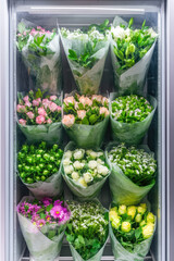 Vending machine with bouquets of fresh flowers, automated flower sales. Small different bouquets of flowers in the showcase of the vending machine.