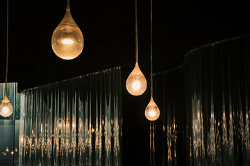 Elegant teardrop pendant lights illuminate a dark interior, creating a warm and inviting ambiance....