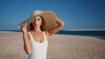 Stylish model posing beach wearing straw hat closeup. Gorgeous woman on shore