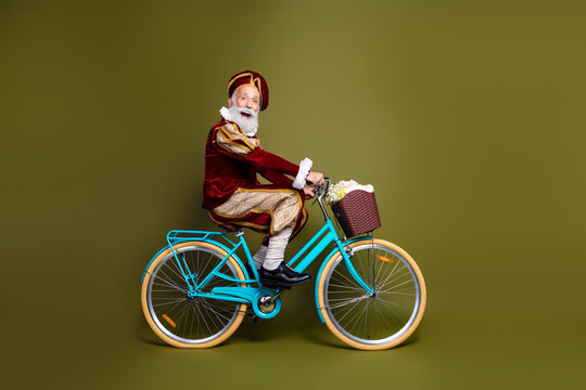 Senior man dressed as a nobleman riding a modern bicycle in costume against a khaki green backdrop