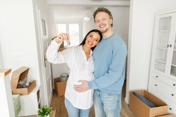 Loving expecting husband and wife showing key from new apartment and smiling at camera, celebrating moving to own house