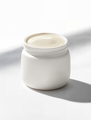 Creamy skincare product in a round container on a smooth surface under bright sunlight