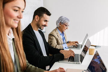 Fototapeta premium Business colleagues collaborating on laptops, demonstrating teamwork and productivity in a modern office environment. Business concept