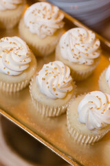anilla cupcakes with swirled frosting and gold sprinkles.