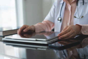 Female doctor working on digital tablet computer at doctor's office, close up