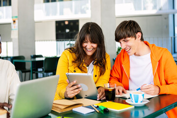 Young group of student friends doing homework or preparing exam together sitting on table at campus college. Education lifestyle concept