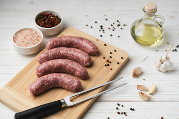 Uncooked grilled sausages on the wooden cutting board