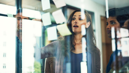 Woman, writing or meeting with team on glass board for project planning, tasks or agenda at office....
