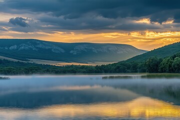 Misty sunrise over mountain lake, calm water reflects colors