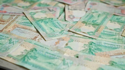 Uae banknotes featuring dirhams scattered across a surface, highlighting the vibrant currency of the united arab emirates in a financial context.