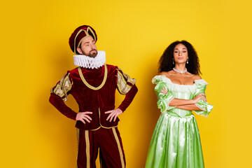Couple in period-specific costumes standing against a vibrant yellow backdrop