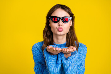 Fashionable young woman with sunglasses expressing joy through gestures on a vibrant yellow...