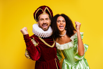 Playful couple in royal costumes celebrating amidst a vibrant yellow background in a fun theme party setting