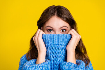 Young woman in blue sweater expressing joy against bright yellow background with casual and trendy...