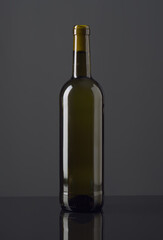 Elegant gray wine bottle displayed on a reflective surface in soft lighting