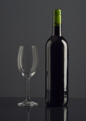 Elegant display of gray wine bottle and empty glass on reflective surface