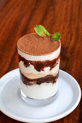 Delicious tiramisu dessert garnished with fresh mint in a glass