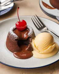 Rich chocolate fondant cake served with ice cream and cherry