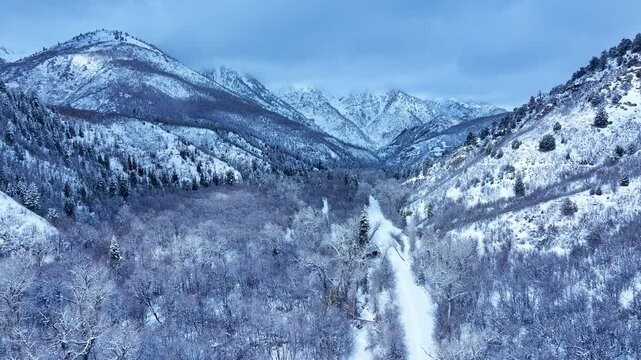 Aerial Mount Nebo Utah snowmobile tracks snow trail 2 pull. Beautiful late winter Wasatch Mountains. Valley and alpine landscape. Cold weather cloud environment. Rocky ledges, cliffs, canyon valleys. 