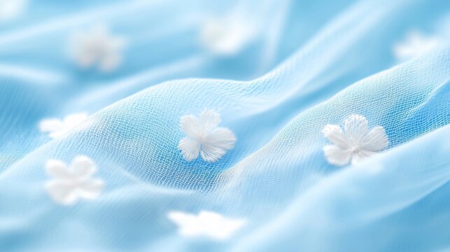 Beautiful close-up of semi-transparent batiste fabric adorned with white floral embellishments against a soft blue background