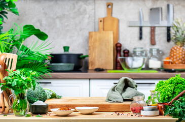 Healthy vegan food, eating, cooking, blogging background. Oak cutting board with vegetables, herbs, broccoliband linen napkin on rustic kitchen with wooden table, kitchenware and ingredients
