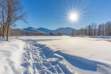 Snow-covered path leading to a frozen lake with mountains and a bright sun in the background.