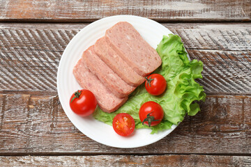 Tasty canned meat, tomatoes and lettuce on wooden table, top view