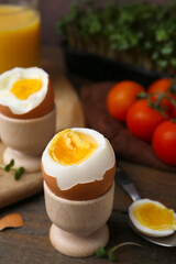 Soft boiled eggs, microgreens and tomatoes on wooden table, selective focus