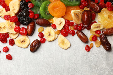 Mix of different dried fruits on gray textured table, top view. Space for text