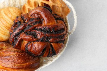 Different pastries in basket on light table, closeup