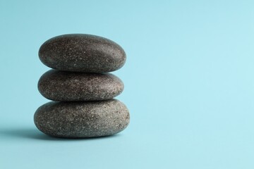 Stack of rocks on light blue background, space for text. Harmony and life balance